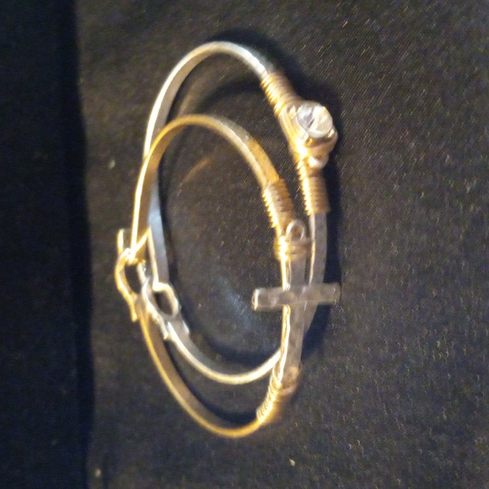 A pair of bracelets with a crystal on one and a cross on the other.